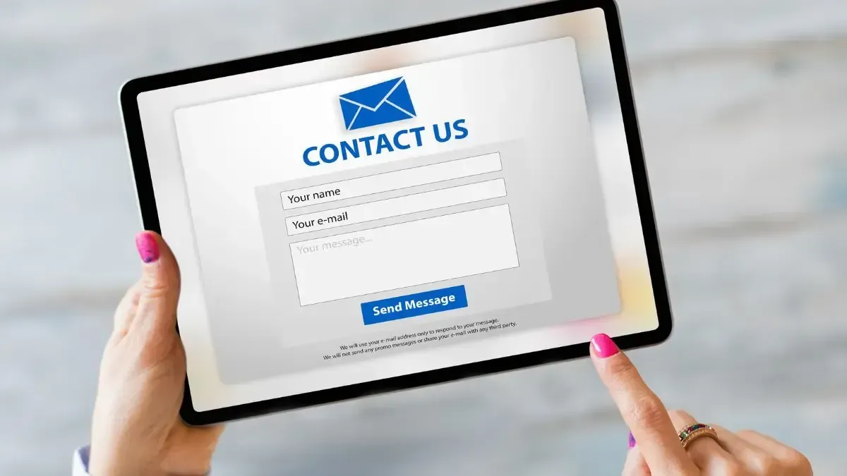 A woman is holding a tablet with a contact us page on it.