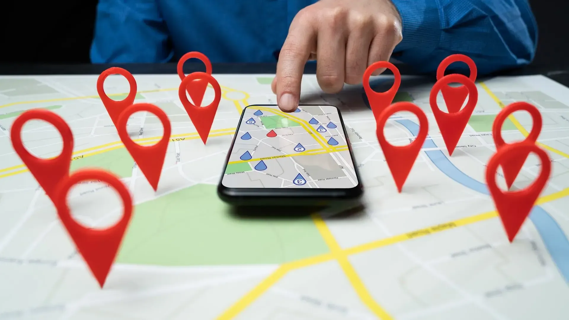 Person uses phone to navigate map surrounded by red location markers.