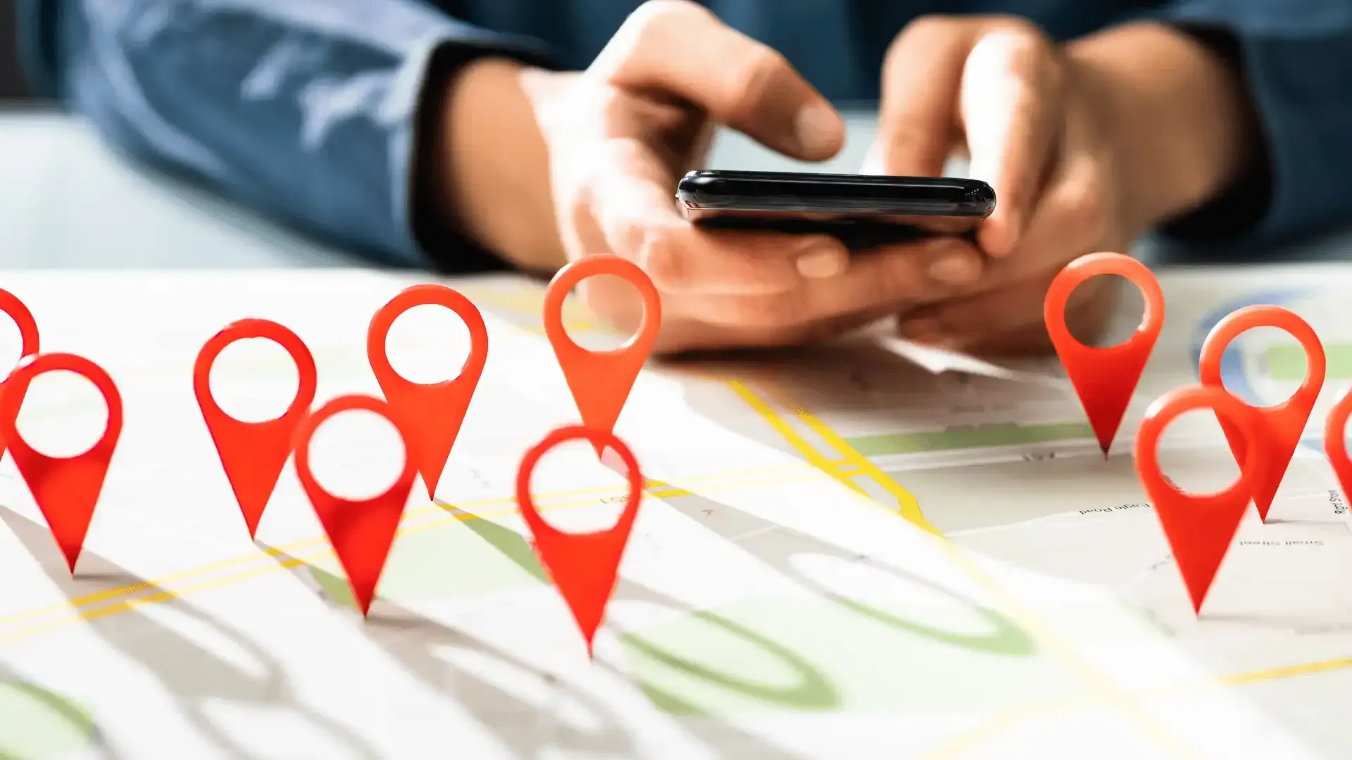 a person is using a cell phone on a map with red pins .