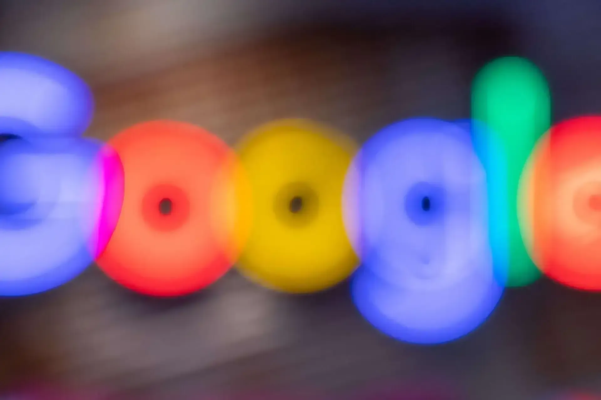 a blurry picture of the google logo in rainbow colours .