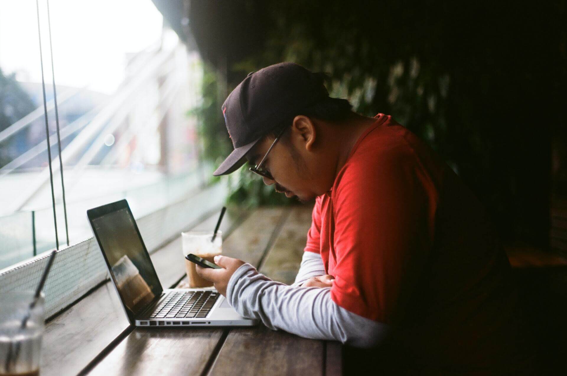 a man is sitting at a table using a laptop computer .