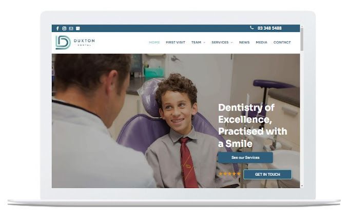 A dentist is talking to a young boy in a dental chair.