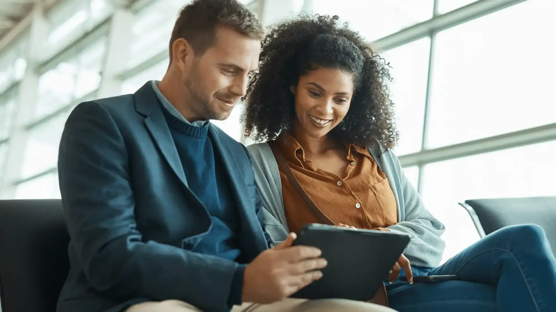 a man and a woman are looking at a tablet together