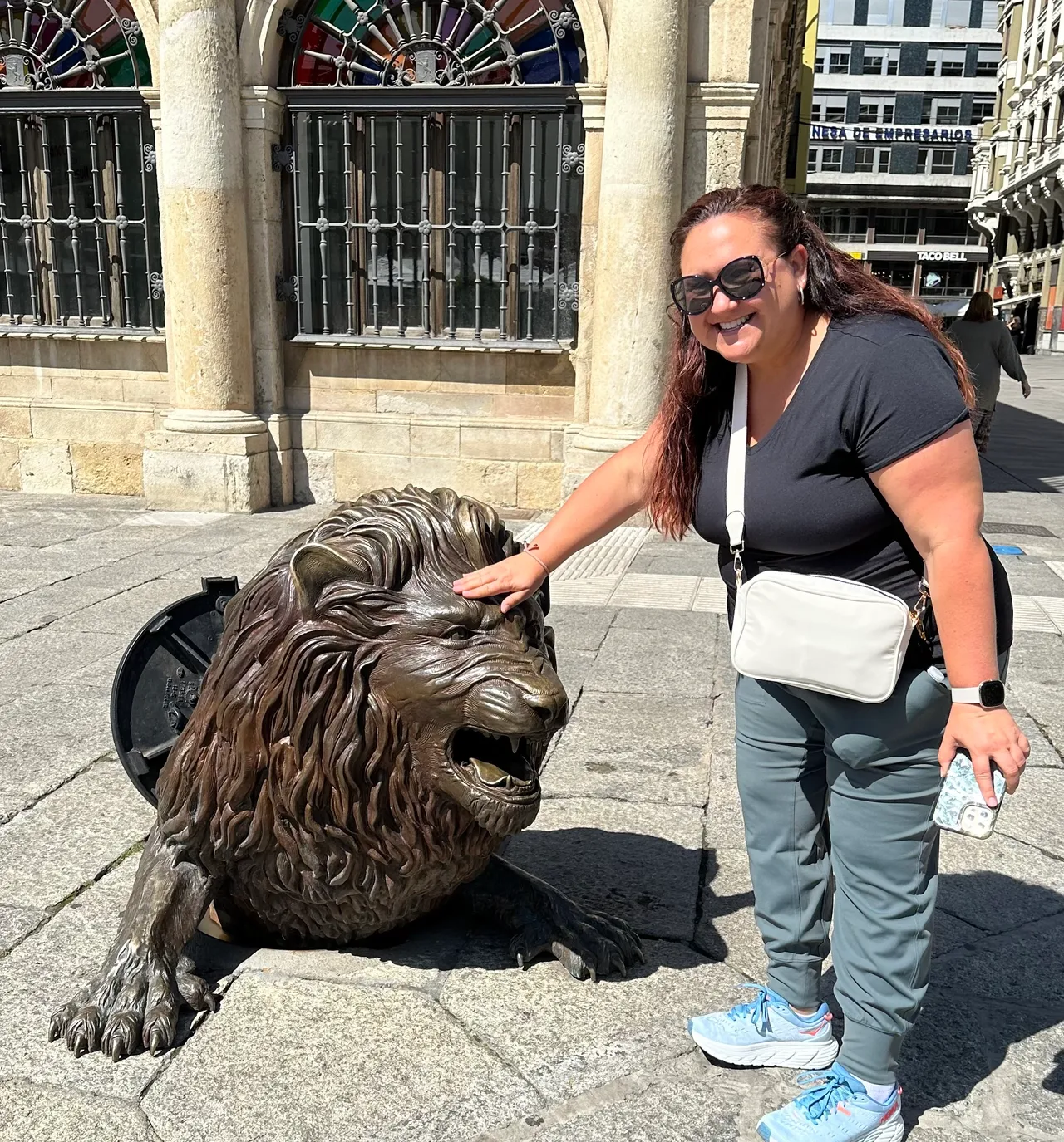 A woman is standing next to a statue of a lion.