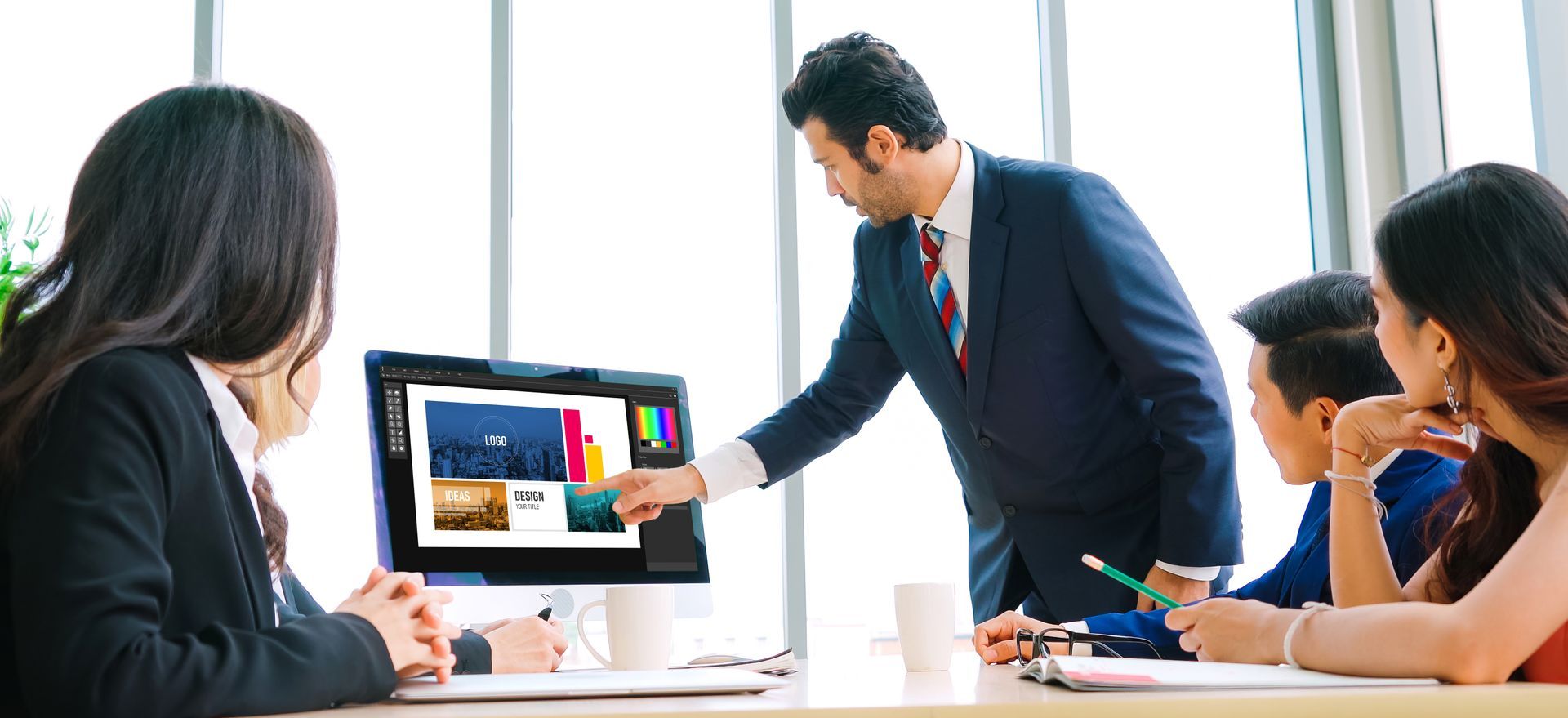 Business team discussing a presentation on a computer screen in a bright office