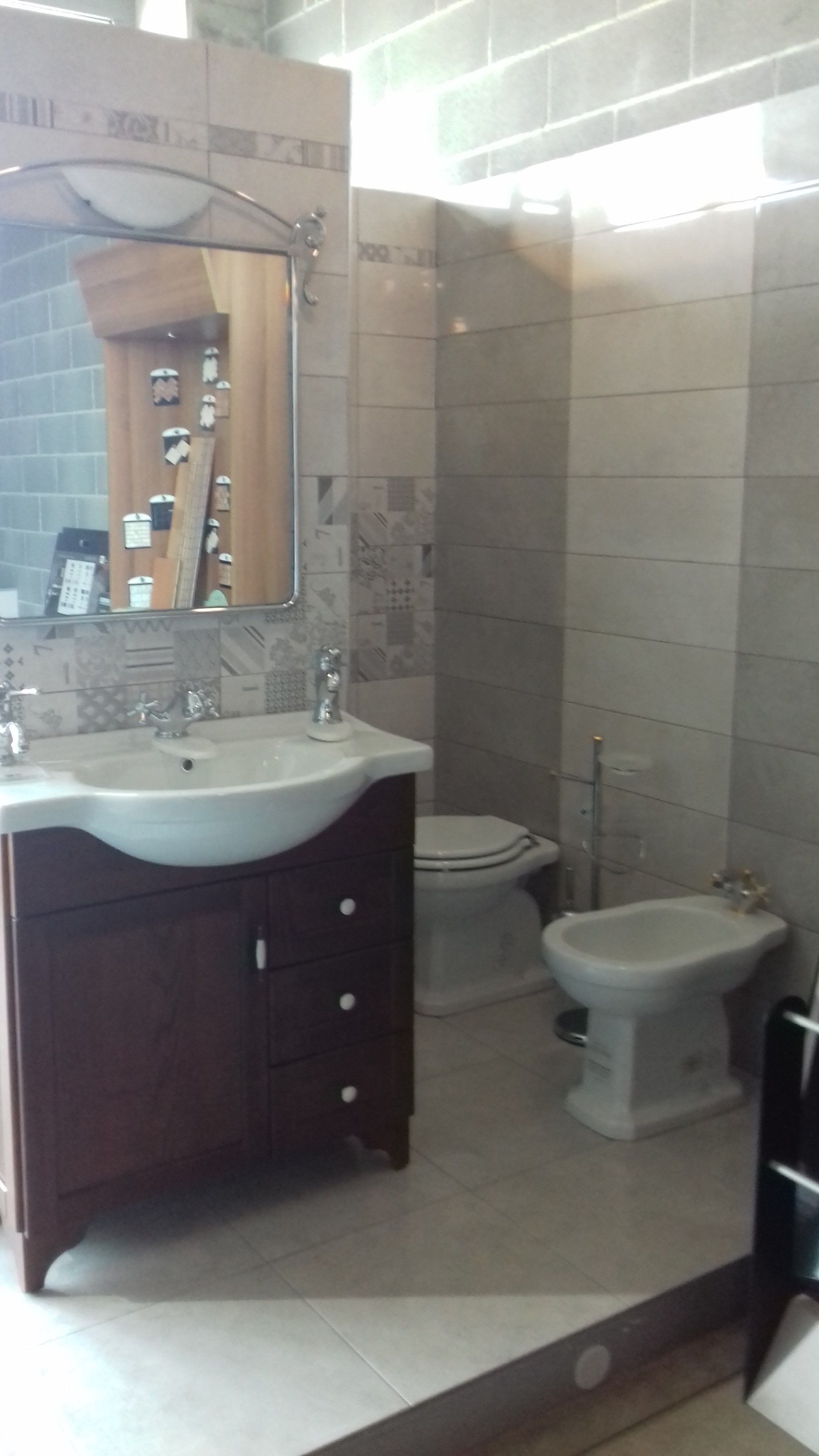 Un bagno con lavandino, water, bidet e specchio.