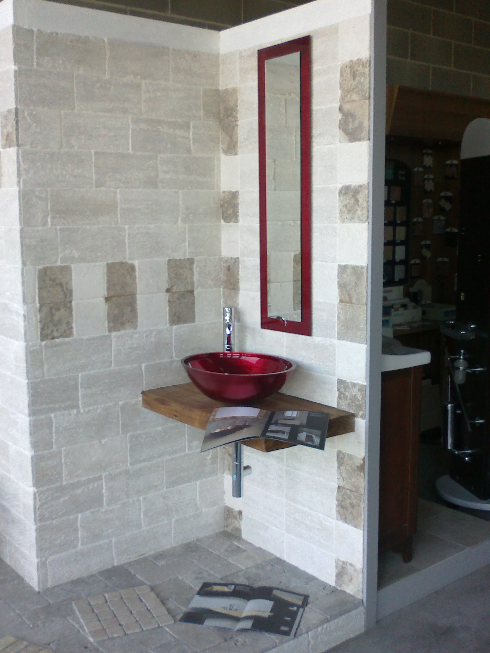 Un bagno con un lavandino rosso e uno specchio