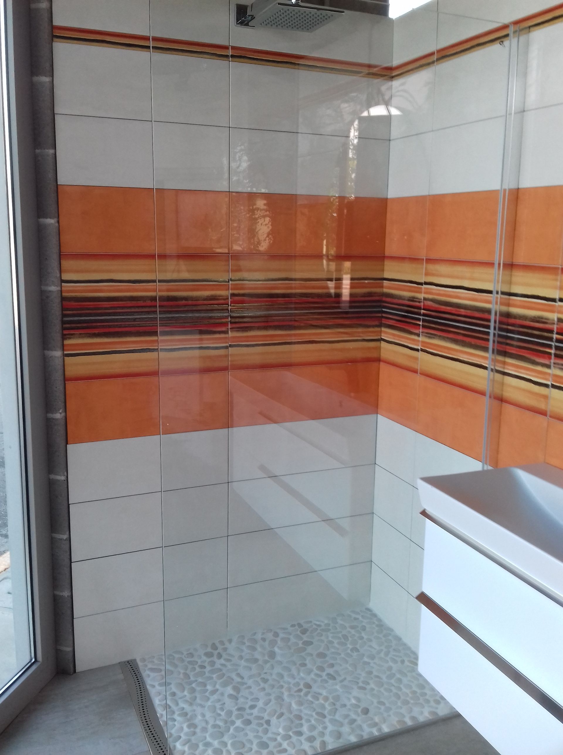 Un bagno con piastrelle arancioni e bianche e una cabina doccia