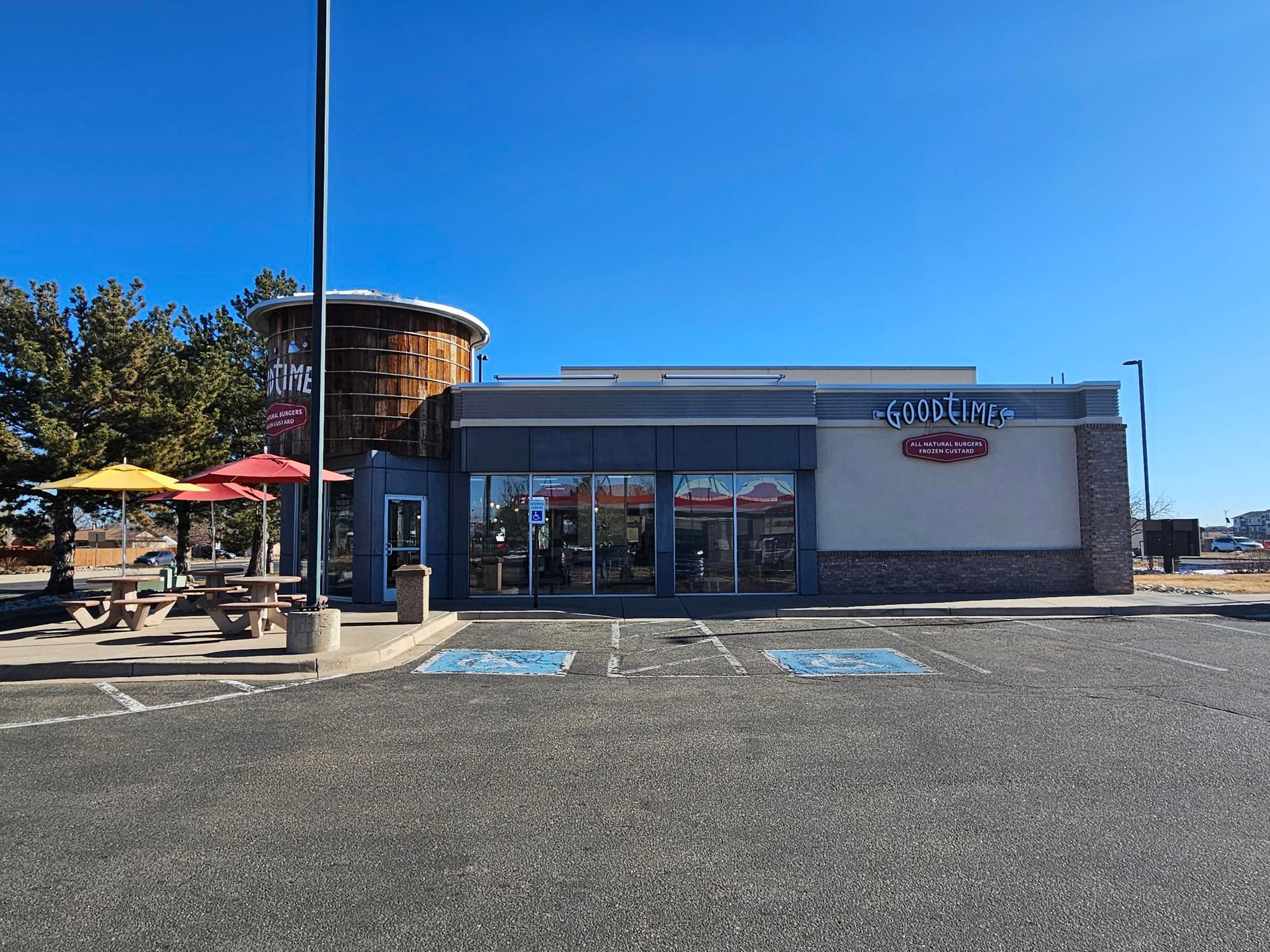 A fast food restaurant with tables and umbrellas in front of it.