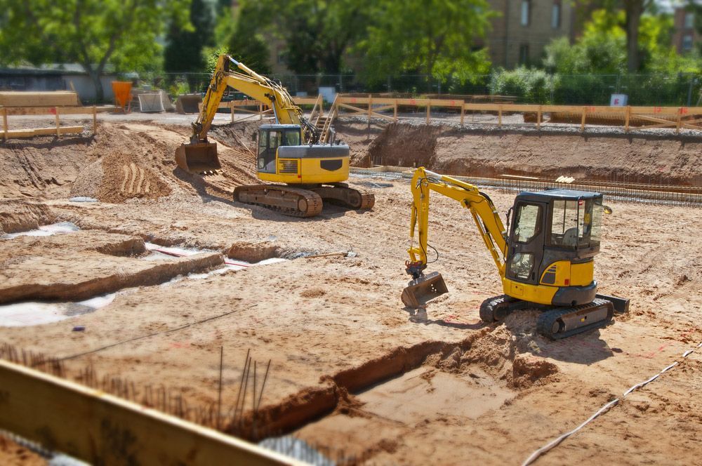 Two yellow excavators are working on a construction site