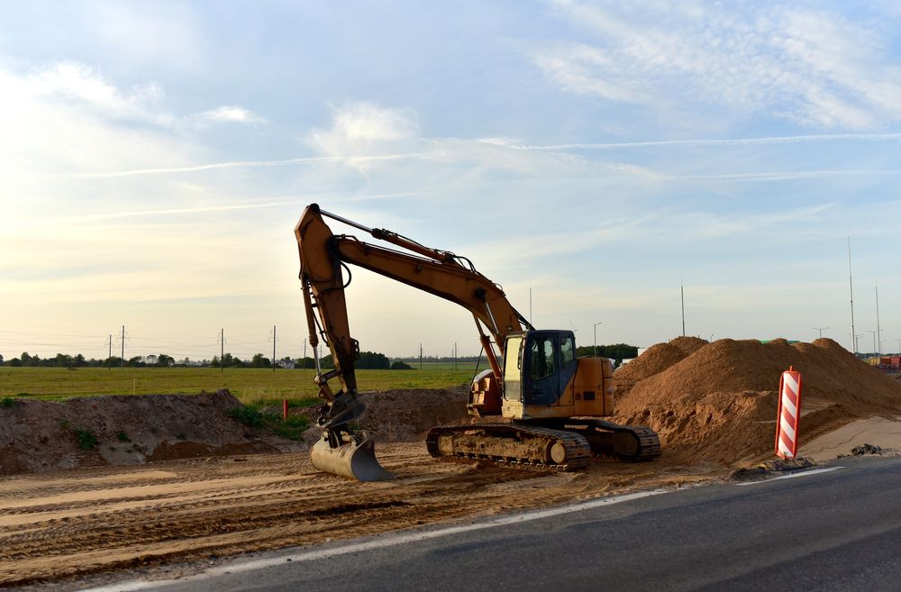 An excavator is working on a construction site next to a road
