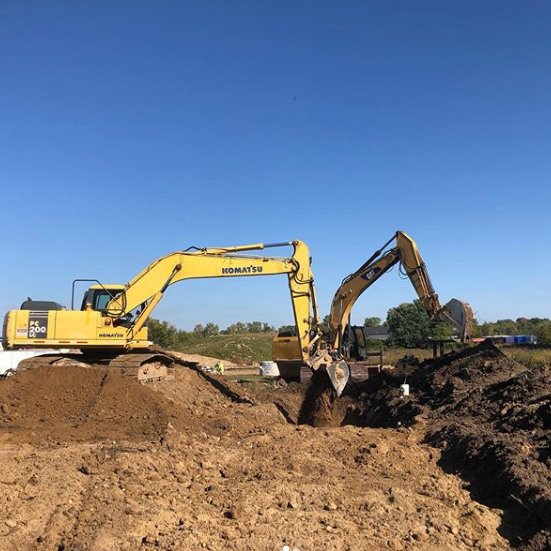 A yellow excavator is digging a hole in the dirt
