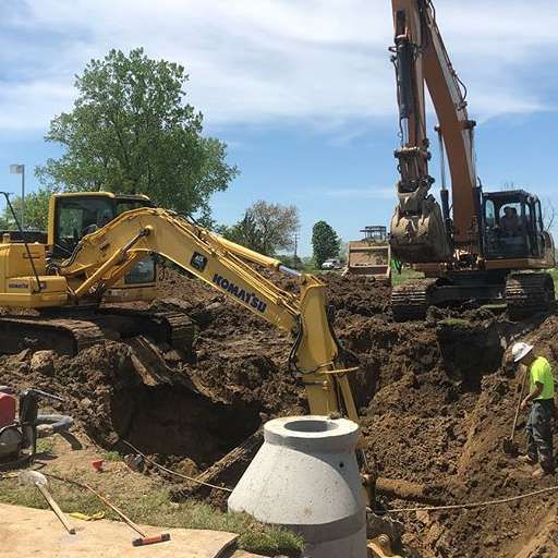 A yellow excavator is digging a hole in the dirt