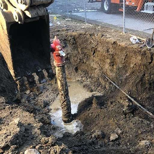 A red pipe in the middle of a muddy hole