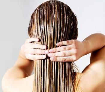 Donna vista di spalle che applica un trattamento sui capelli: soluzioni tricologiche per cura e benessere dei capelli