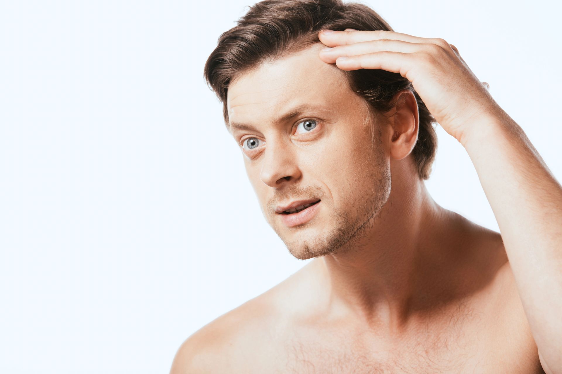 Uomo preoccupato che tocca l'attaccatura frontale: tecniche per infoltire i capelli sulla fronte