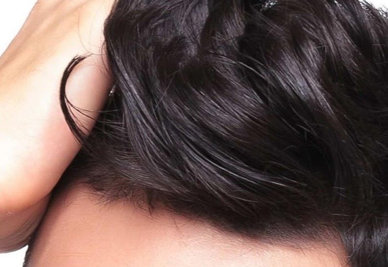 Mano che solleva ciocca di capelli scuri e folti: gli impianti protesici HairAid certificati come dispositivi medici