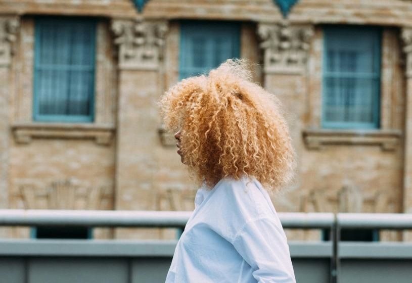 Donna con capelli ricci e voluminosi in ambiente esterno: sindrome dei capelli lanosi, cause e rimedi
