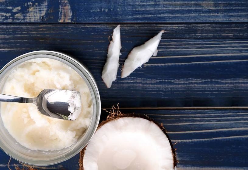 Cucchiaio con olio di cocco e ingredienti naturali su sfondo scuro: rimedi naturali per la caduta