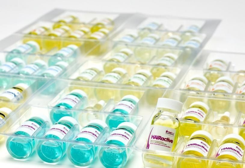 Vassoi di plastica trasparente con bottiglie e lattine di bevande colorate su una superficie bianca