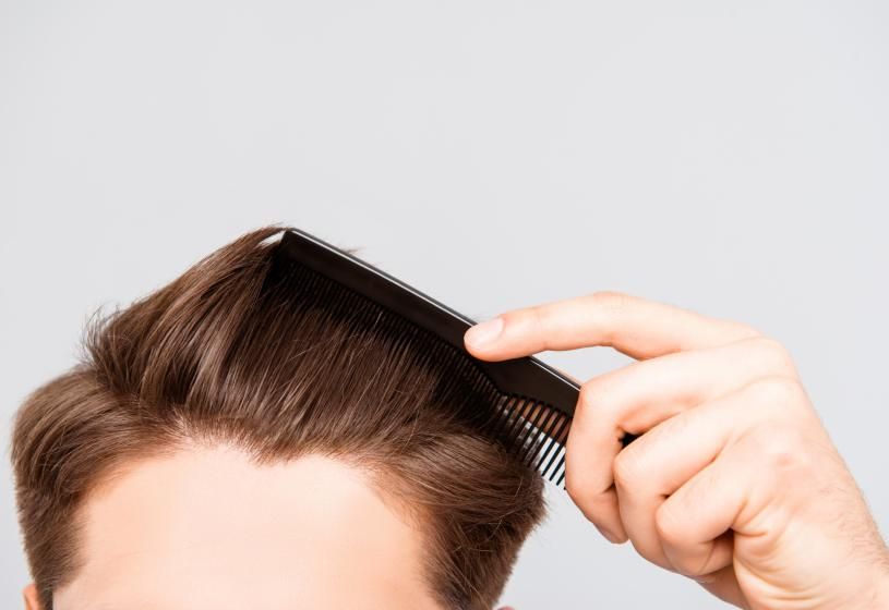 Mano che pettina capelli corti: le 7 cause principali del rallentamento nella crescita dei capelli