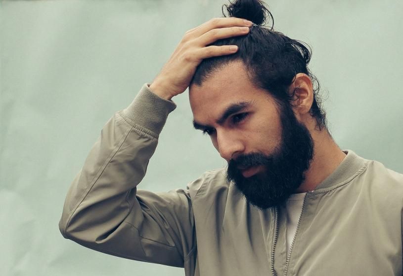 Uomo con capelli rovinati che si passa le mani tra i capelli: cause dei capelli fragili alla radice