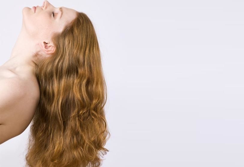 Donna di profilo con capelli lunghi mossi e voluminosi: infoltimento dei capelli non chirurgico, una scelta poco invasiva