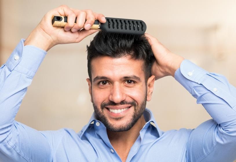 Uomo sorridente mentre si pettina: sedi HairAid in Toscana e Nord Italia per la patch cutanea