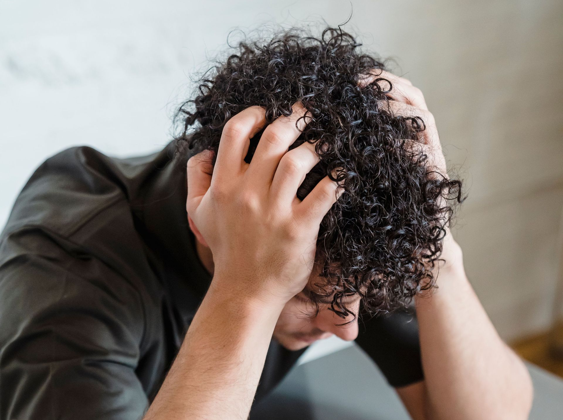Persona sotto stress con le mani tra i capelli: rimedi per la caduta da stress