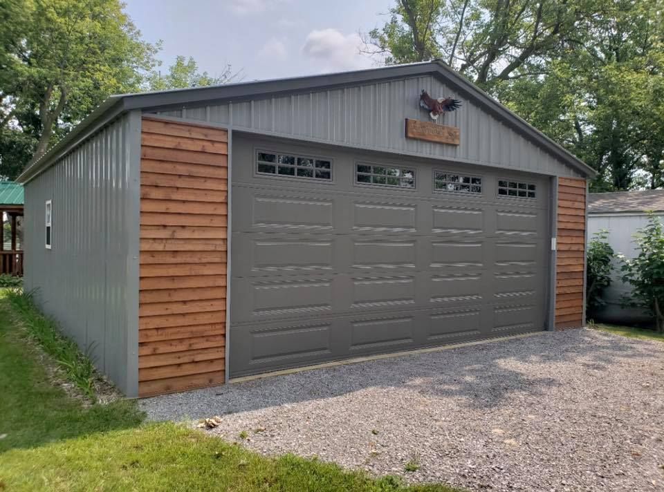 a gray garage with a wooden siding and a large garage door .