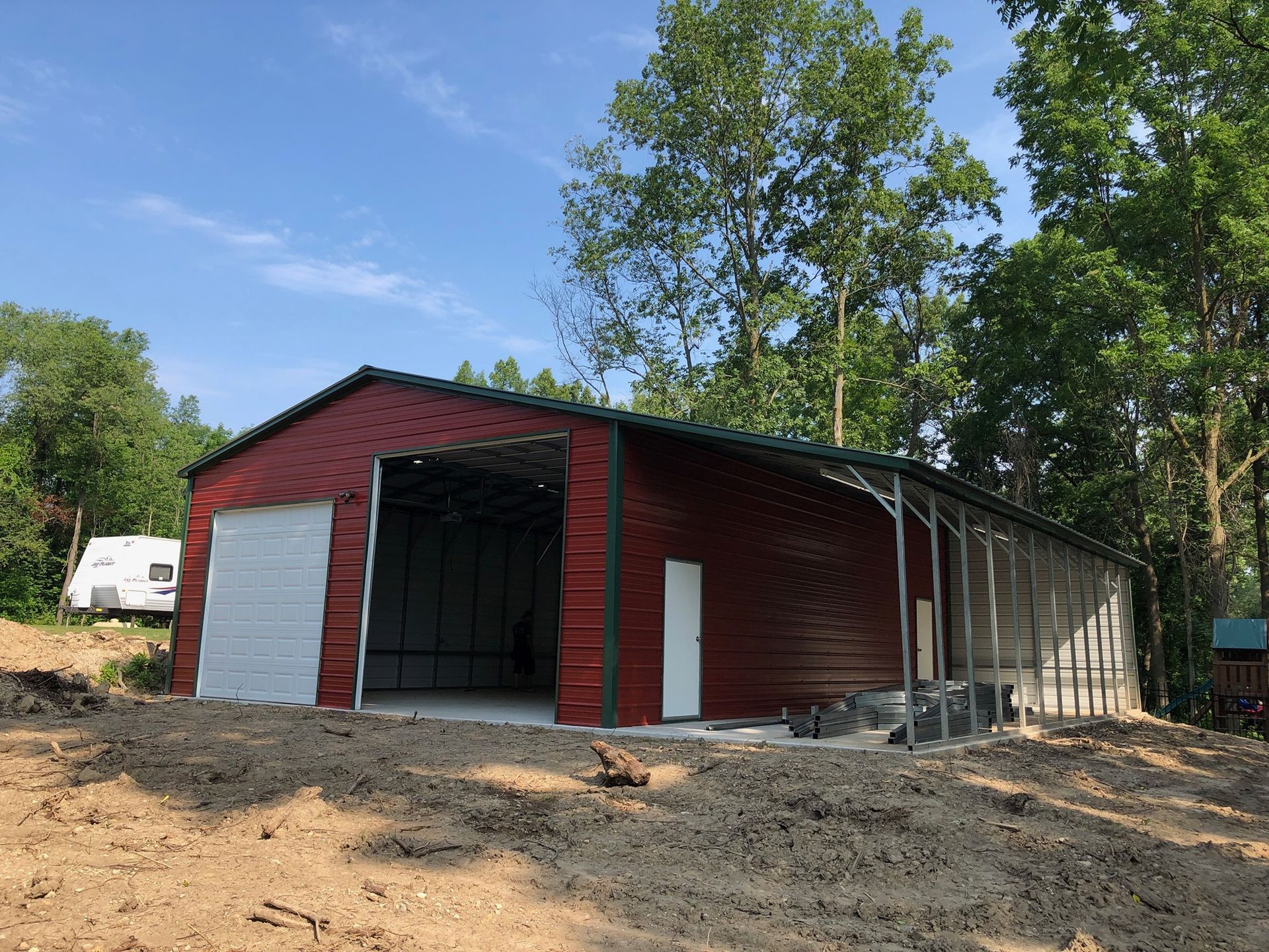 a large red building with a white garage door is sitting on top of a dirt hill .