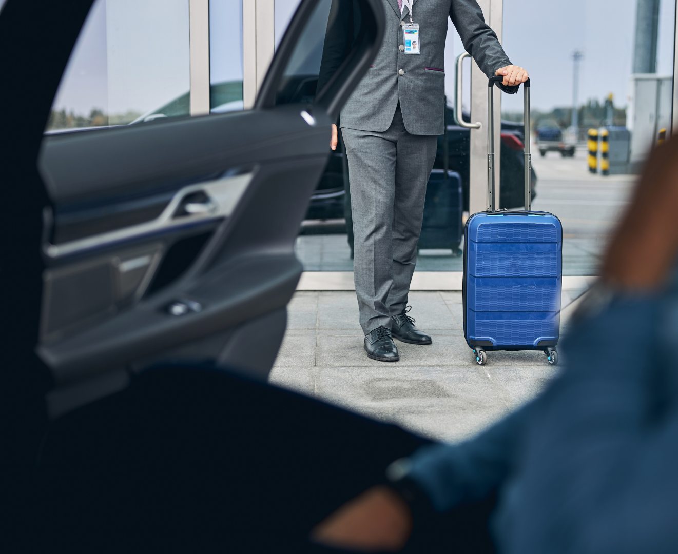 A car is parked on a runway with an airplane in the background.