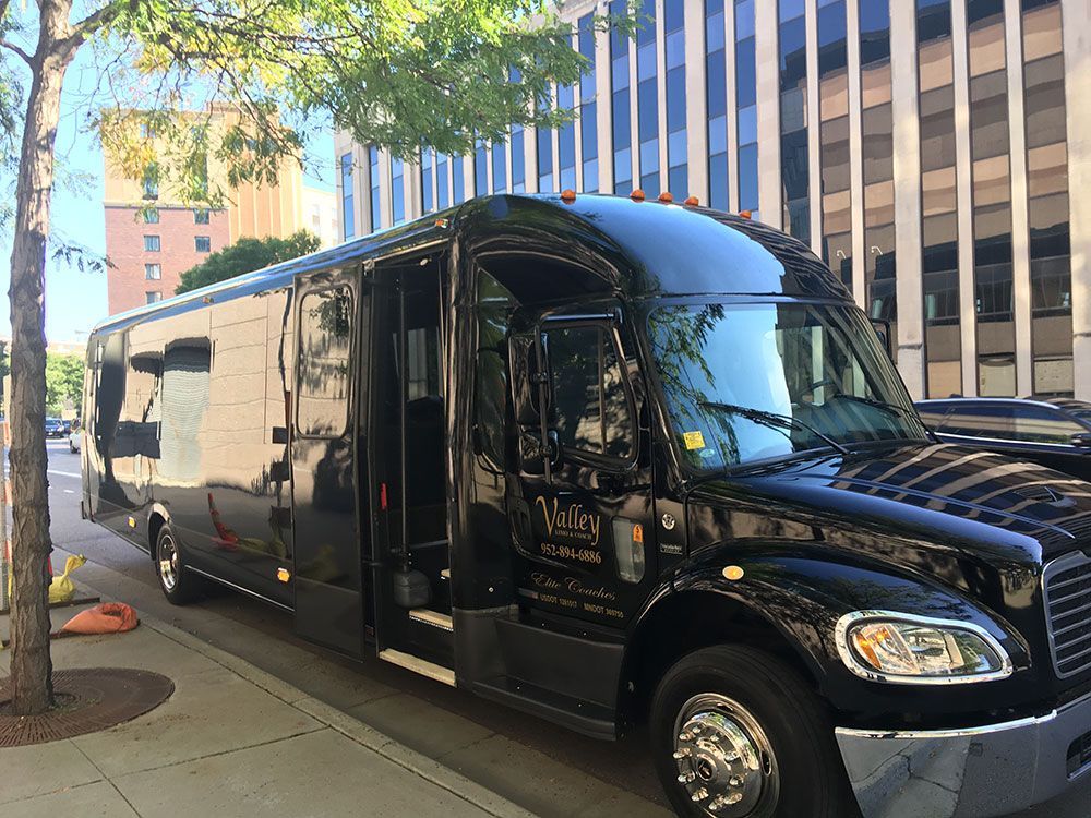 A black bus is parked on the side of the road in front of a building.