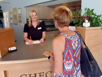 a woman is sitting at a counter talking to another woman