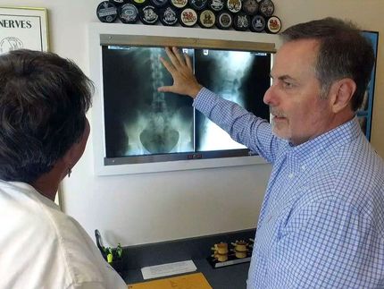 a man is pointing at an x-ray of a person 's back
