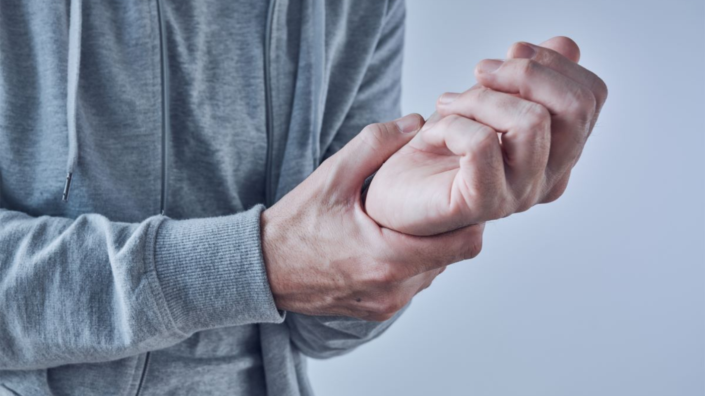 Person in gray hoodie holds wrist, possibly in pain near Raeford, NC.