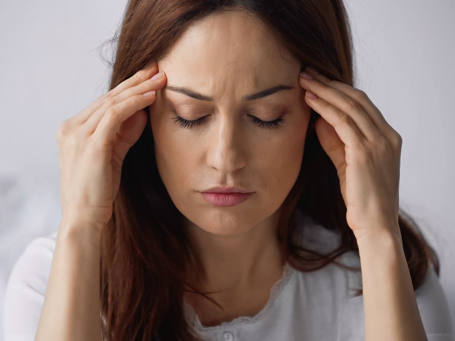 a woman is holding her head in pain .