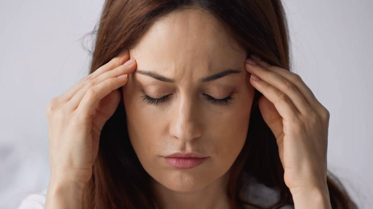 Woman with closed eyes, holding temples, appears to be in pain or experiencing headache near Raeford, NC.