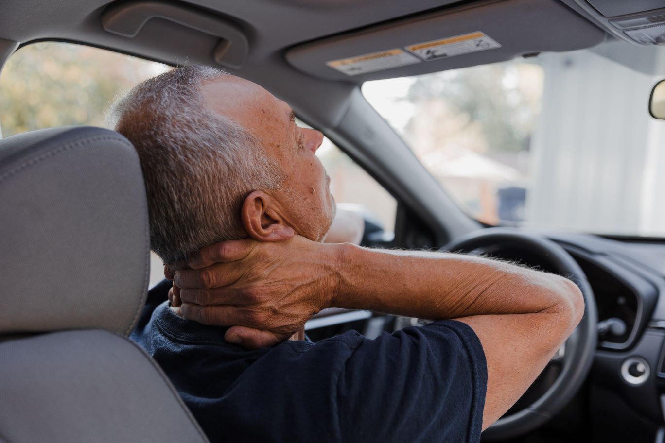 Man in car holding his neck, appearing to be in pain in Hope Mills, NC.