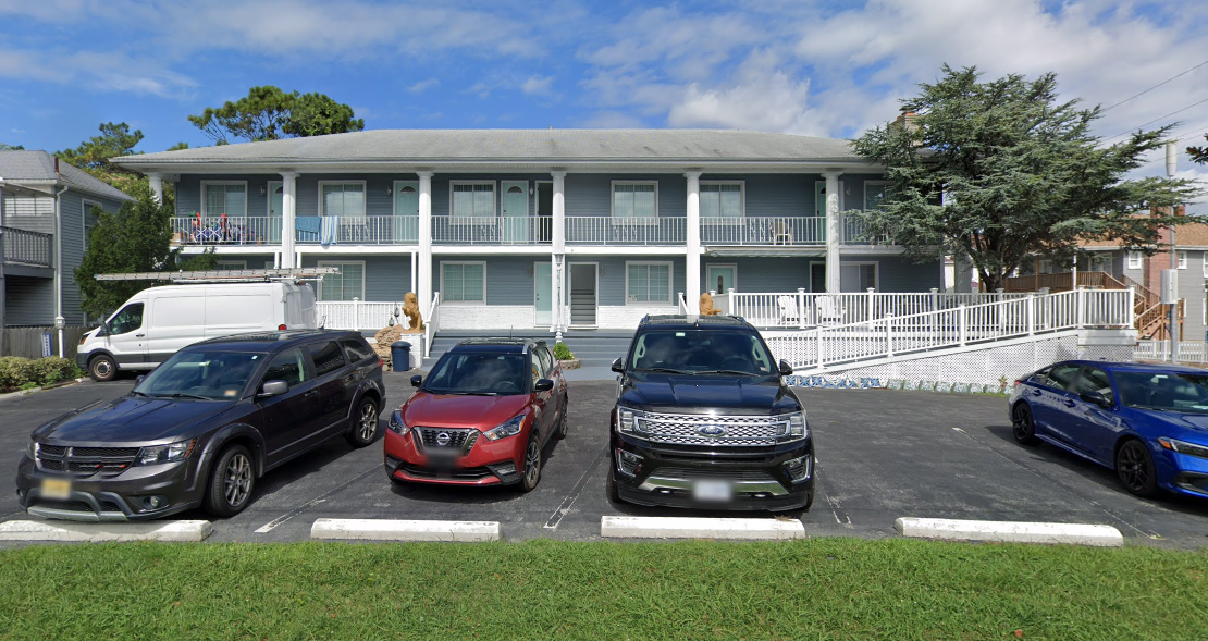A row of cars are parked in front of a building.