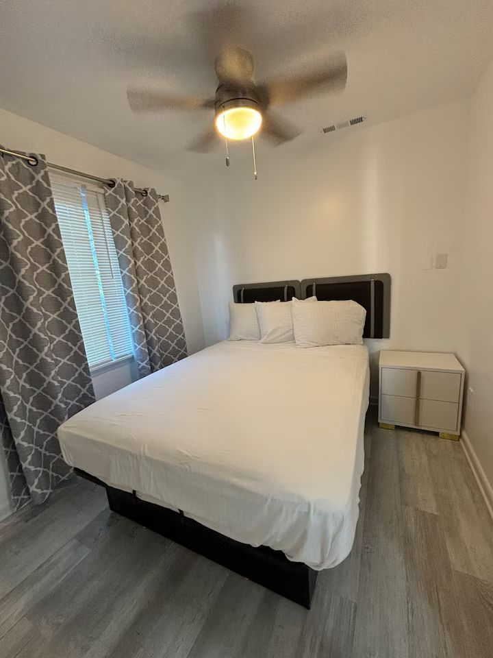 A bedroom with a bed , nightstand , and ceiling fan.