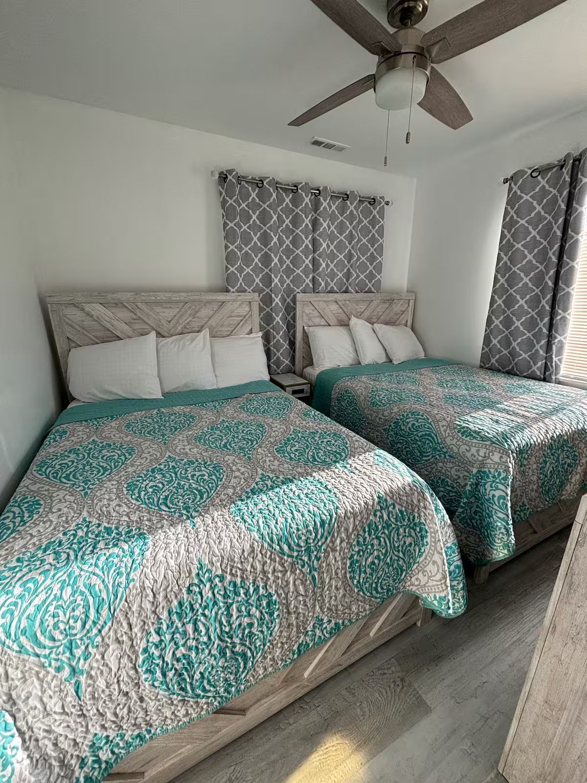 A bedroom with two beds and a ceiling fan.