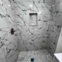 A bathroom with marble tiles and a walk in shower.