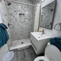 A bathroom with a toilet , sink , shower and mirror.