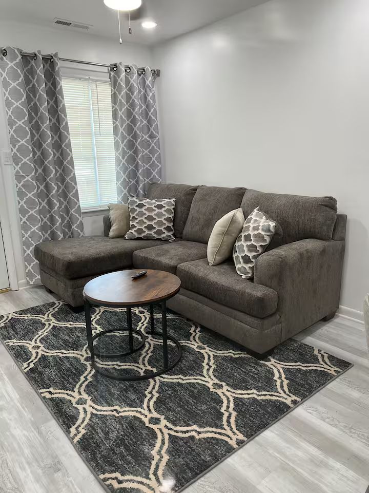 A living room with a couch , coffee table , and rug.