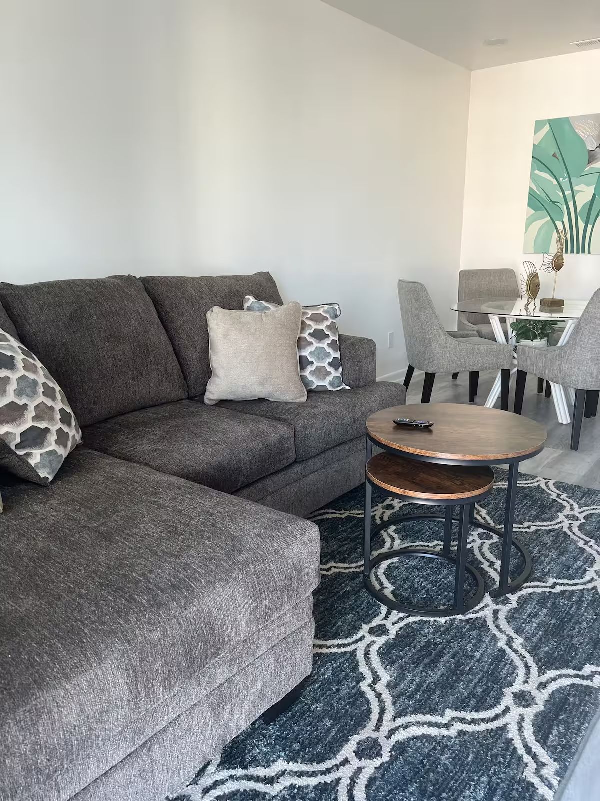 A living room with a couch , table , chairs and a rug.