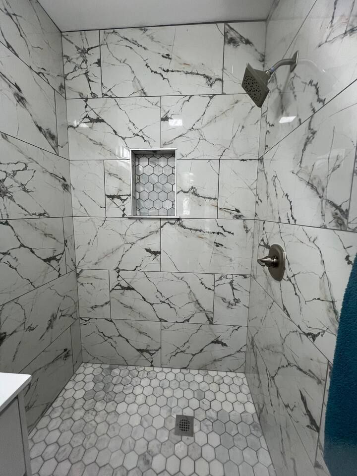 A bathroom with marble tiles and a walk in shower.