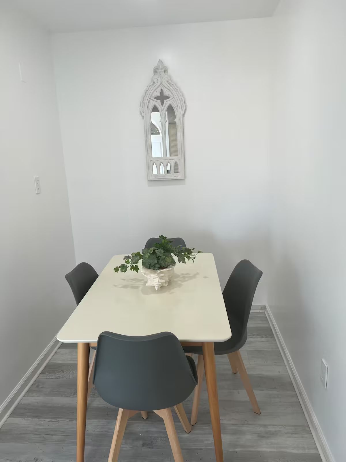 A dining room with a table and chairs and a mirror on the wall