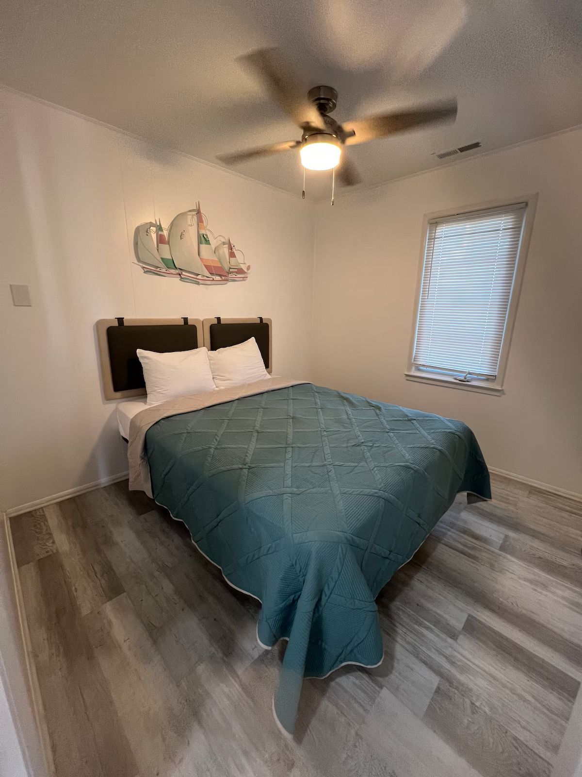 A bedroom with a bed and a ceiling fan.