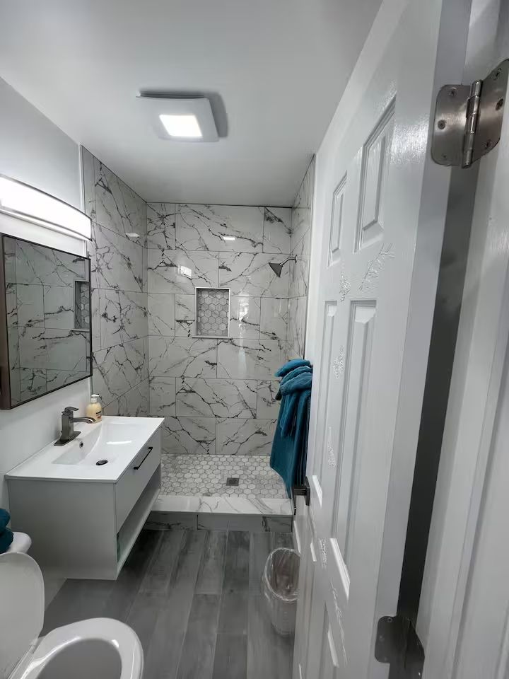 A bathroom with a toilet , sink , mirror and shower.